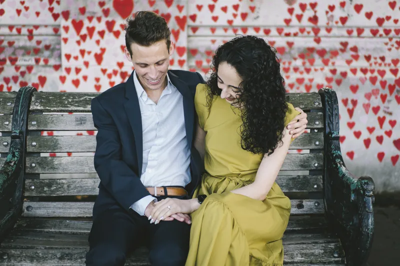 Parmida and Jake admiring the ring beside a wall of painted hearts