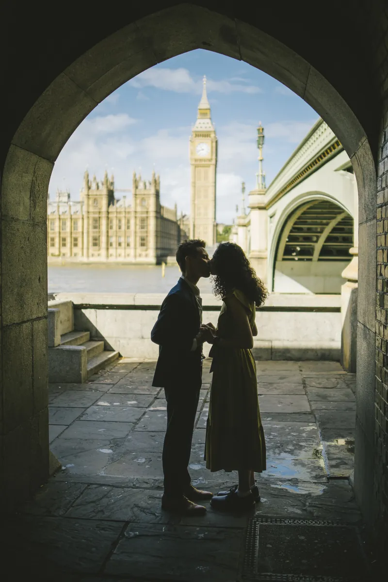 Parmida and Jake sharing a kiss beneath a stone arch